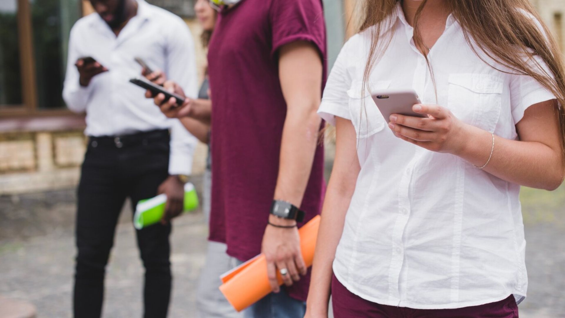 people standing holding smartphones and notebooks